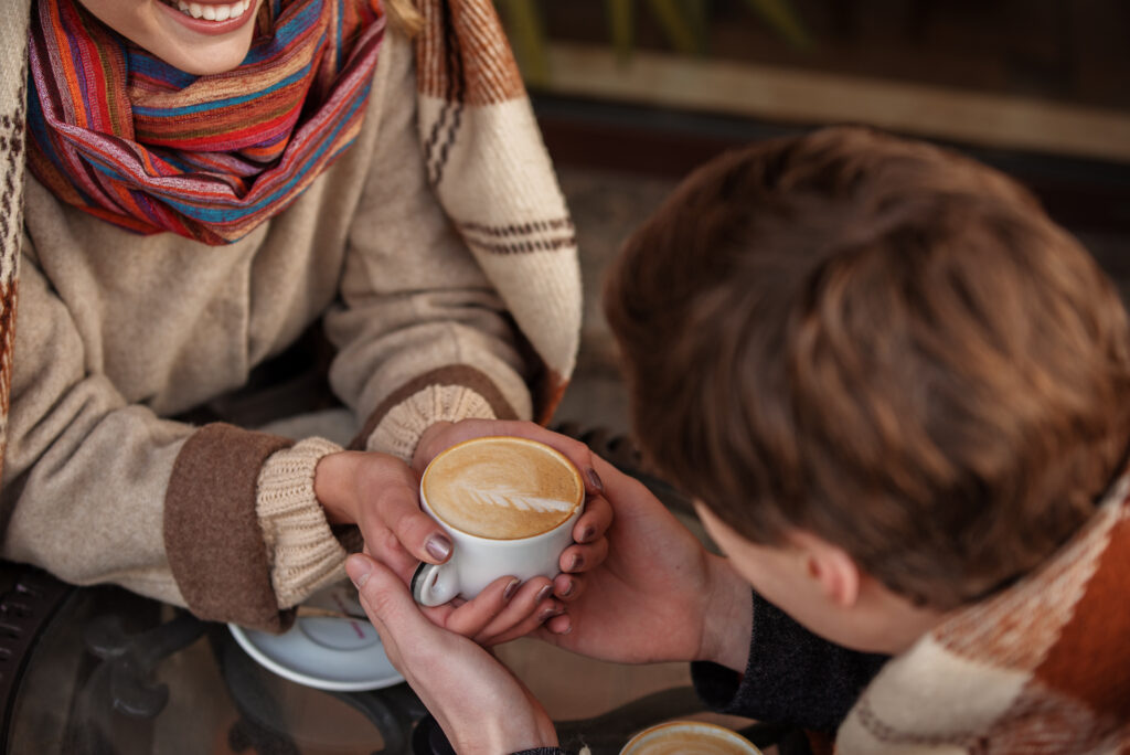couple enjoys coffee together outside, holding hands.