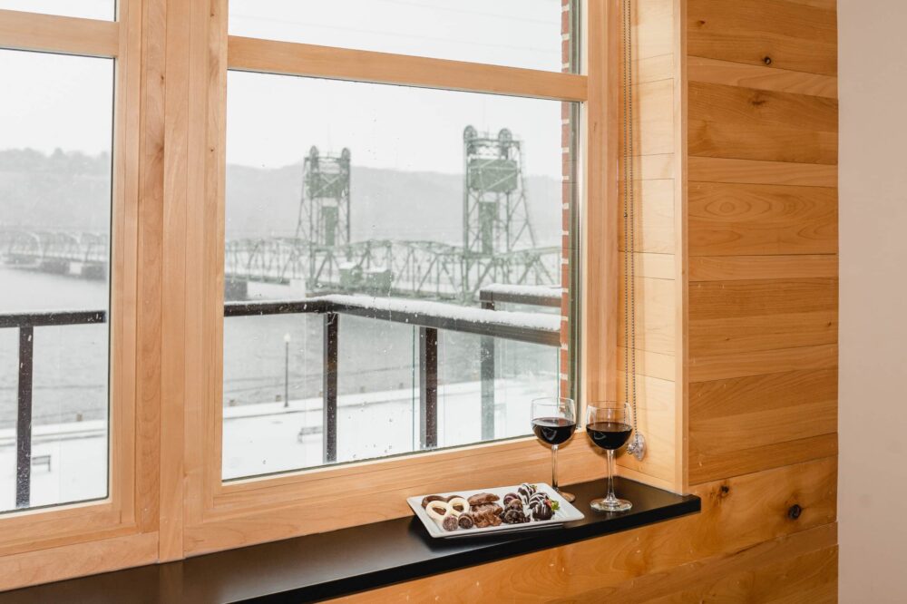 The view of Historic Lift Bridge, glass of wine, and chocolate add-on from a suite at one of the most romantic hotels in Stillwater MN on your weekend getaways for couples in MN.