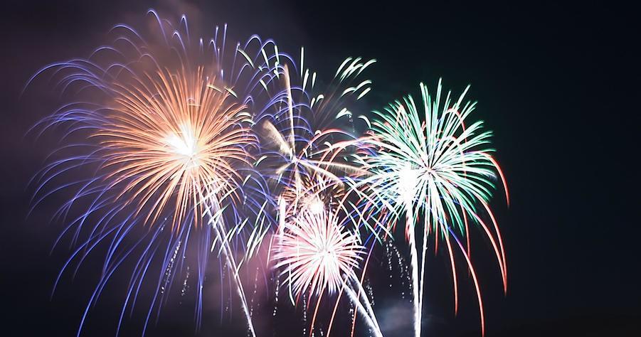 Bright, multi-colored fireworks explode against a dark night sky.