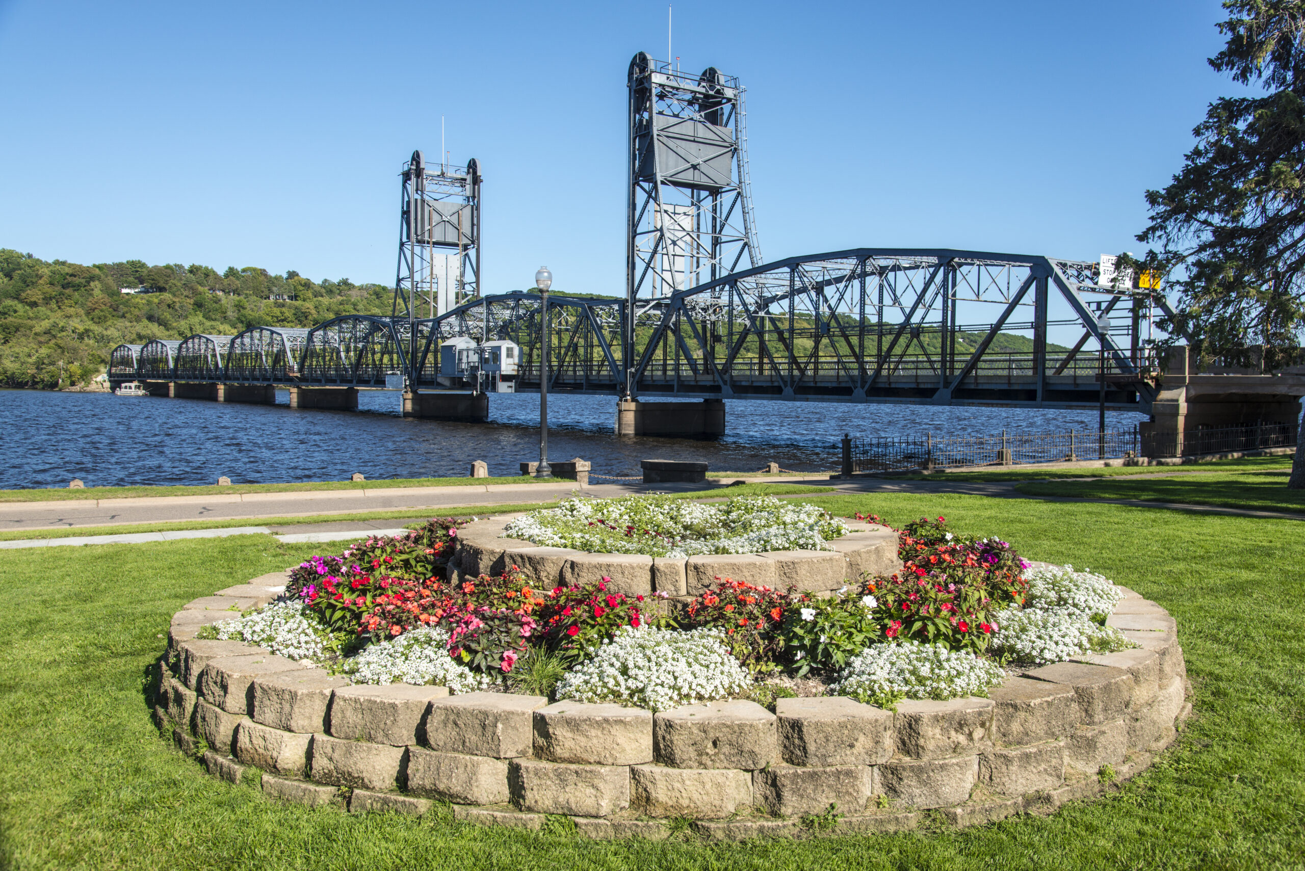 A flower bed in the foreground with the historic Stillwater liftbridge in the background on the St. Croix River.
