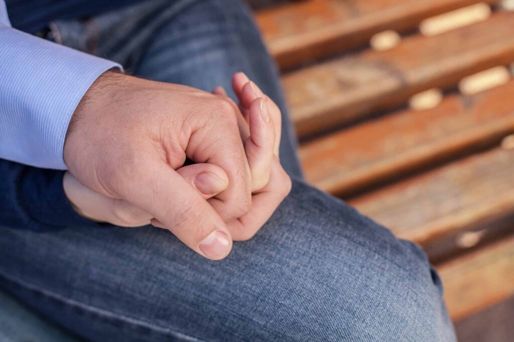 Two people holding hands while sitting on a wooden bench.